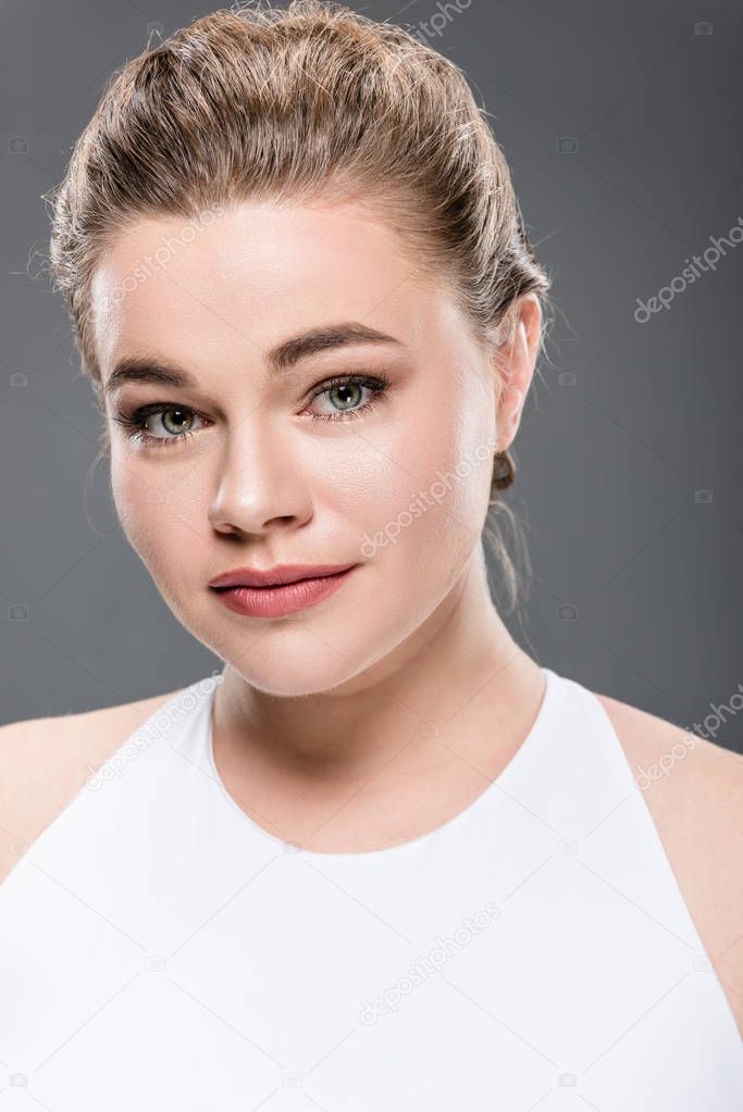 close-up portrait of beautiful young size plus woman looking at camera isolated on grey