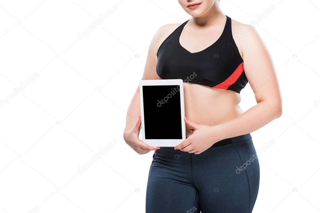 cropped shot of young overweight woman in sportswear holding digital tablet isolated on white 