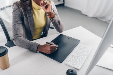 kısmi Afro-Amerikan Tasarımcısı modern ofis masasında grafik tablet kullanarak görünümünü