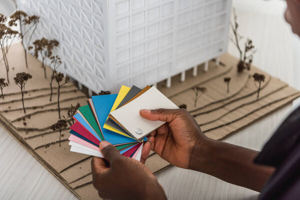 cropped view of african american adult female architect holding color palettes and working on construction project 