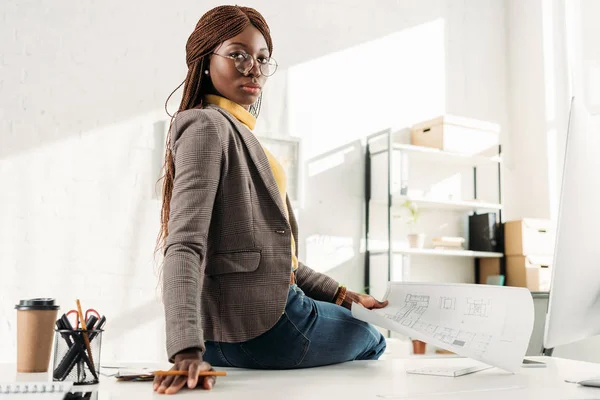 Confiada Arquitecta Afroamericana Gafas Mirando Cámara Sosteniendo Plano Oficina — Foto de Stock