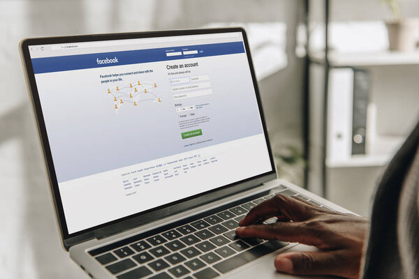 cropped view of african american businessperson using laptop with facebook website on screen