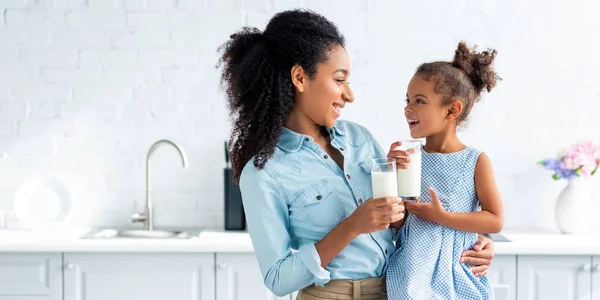 Glimlachend Afro Amerikaanse Moeder Dochter Houden Glazen Melk Keuken Kijken — Stockfoto