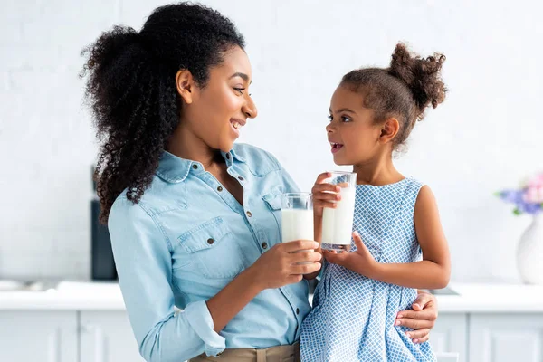 Alegre Afro Americana Mãe Filha Segurando Copos Leite Cozinha Olhando — Fotografia de Stock