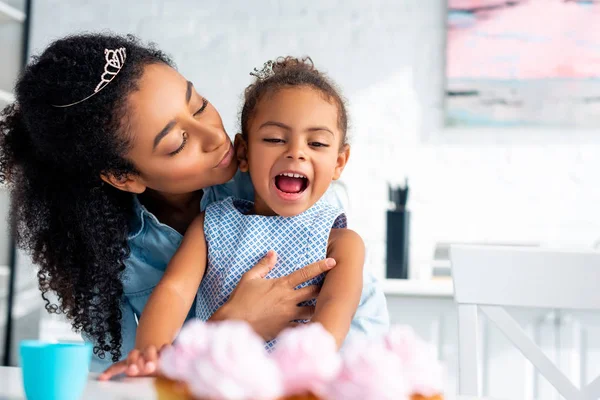 Afro Amerikaanse Moeder Knuffelen Opgewonden Dochter Aan Tafel Met Cupcakes — Gratis stockfoto