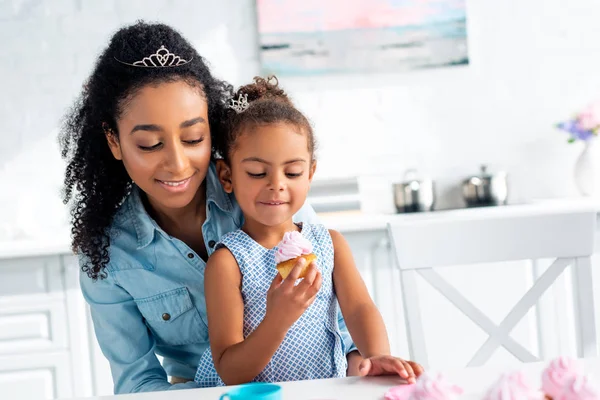 アフリカ系アメリカ人の母と娘が台所でケーキを見て  — 無料ストックフォト