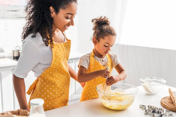 アフリカ系アメリカ人の娘と母の台所で生地を Whisking の準備と — ストック写真