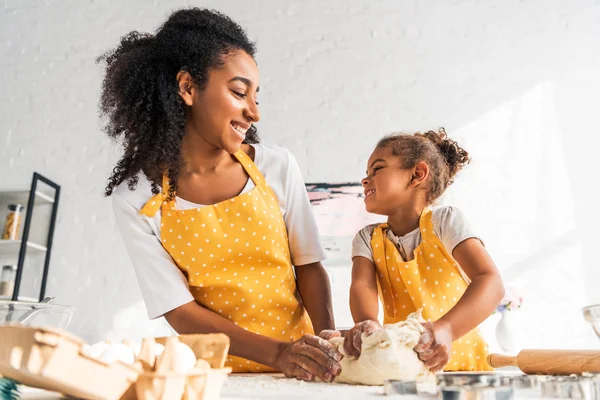 Gülümseyen Afrikalı Amerikalı Anne Kızı Hamur Yoğurma Birbirine Mutfakta Bakarak — Ücretsiz Stok Fotoğraf