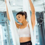 Atraktivní sportovní dívka cvičí jógu v houpací síti ve studiu