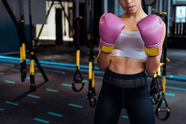 Partial view of  female boxer in pink boxing  gloves practicing boxing in gym  clipart