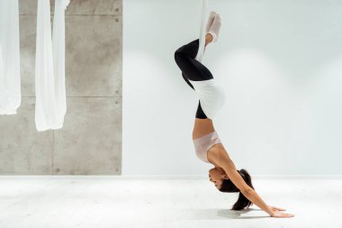 Sportif kız yoga stüdyosu Anti yerçekimi yoga ve ters pozisyonda pratik yaparken rahatlatıcı