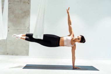 Attractive strong female practicing antigravity yoga in hammock in studio clipart