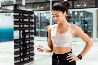 Çekici sportif kız kalça jimnastik içinde elleriyle dururken müzik dinlemek