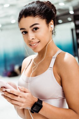 Çekici gülümseyen Afro-Amerikan Kız fitness salonunda müzik dinlemek