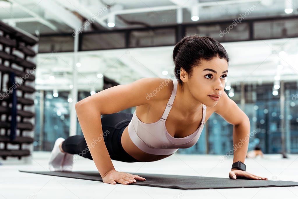 Wonderful young girl doing push ups on mat in fitness gym