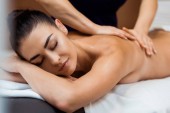 schöne junge Frau mit geschlossenen Augen bei einer Massage im Wellnessbereich 