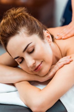 mutlu genç kadın kapalı gözlerle spa salonda masaj keyfi