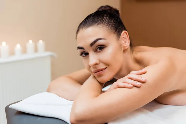 Jovem Atraente Deitado Mesa Massagem Sorrindo Para Câmera Spa — Fotografia de Stock