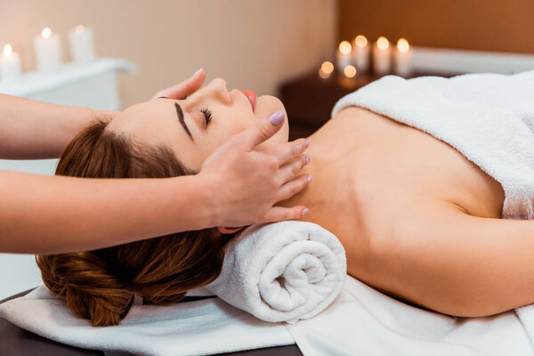 side view of young woman having facial massage in spa salon