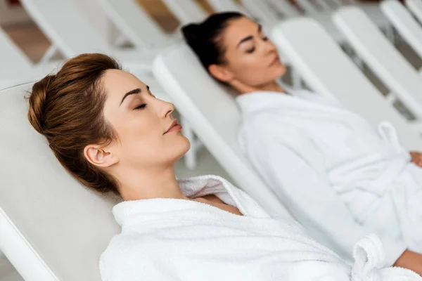 Attractive Young Women Bathrobes Lying Closed Eyes Sunbeds Spa — Stock Photo, Image