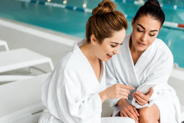 Glückliche Junge Frauen Bademänteln Mit Smartphone Während Sie Sich Wellnessbereich — kostenloses Stockfoto