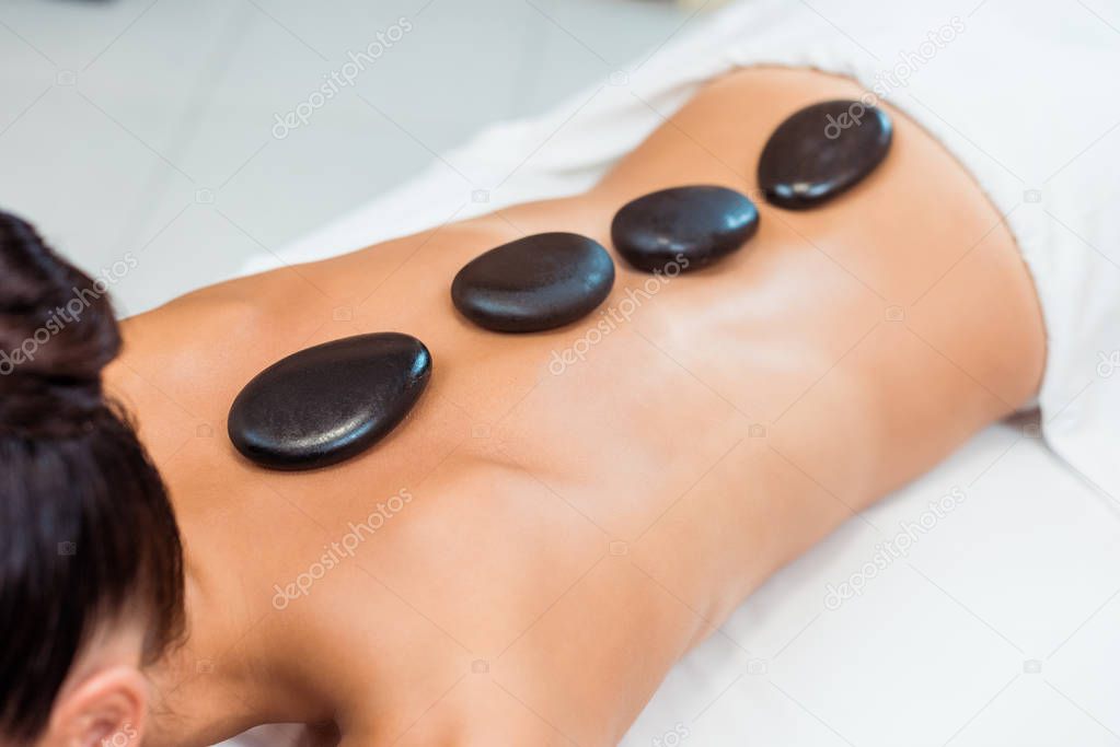 cropped shot of young woman having hot stone massage 