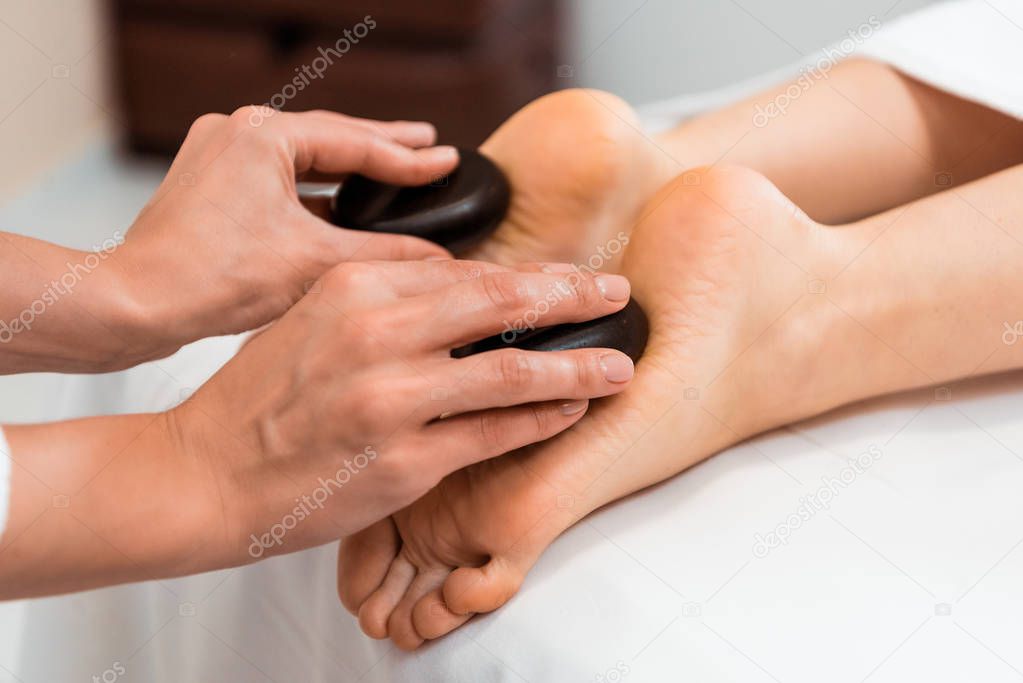 close-up partial view of woman having hot stone massage in spa salon