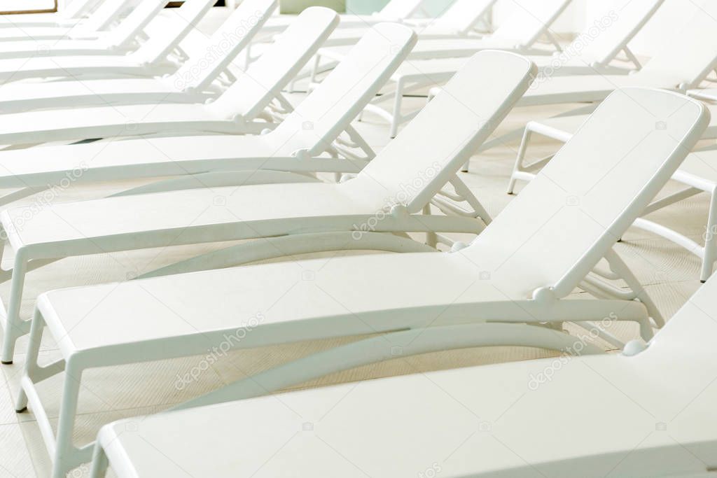 empty white sunbeds in modern spa center