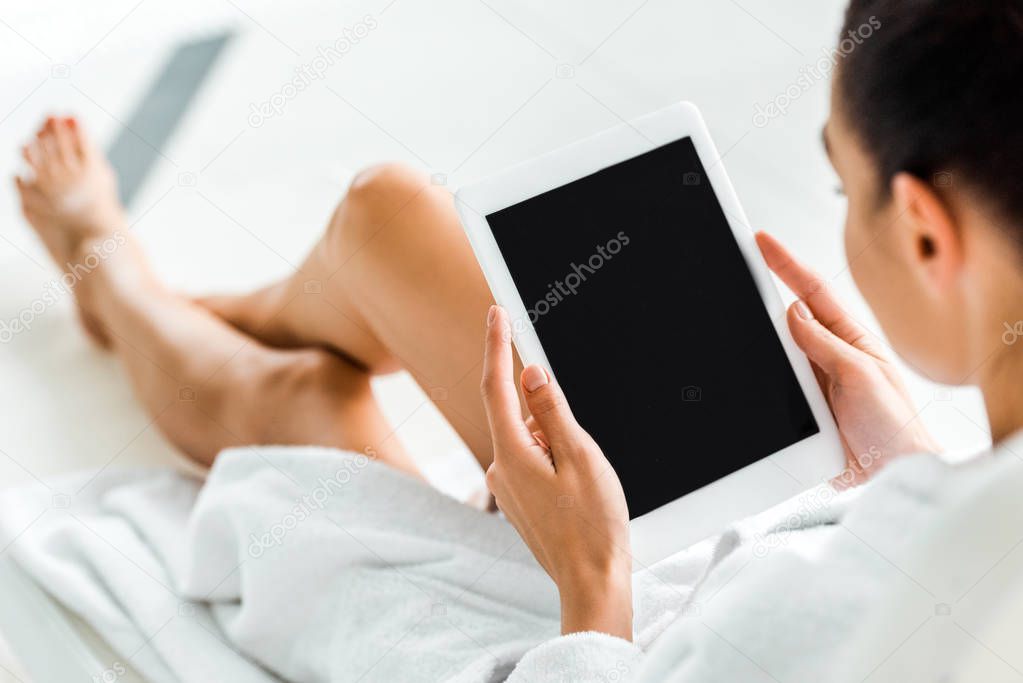 cropped shot of woman in bathrobe using digital tablet with blank screen in spa