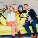 Happy family sitting on couch with ski accessories and packing for winter holidays, travel concept