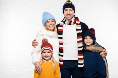 gülümseyen aile sarılma ve beyaz arka plan üzerinde kameraya bakarak kış giysileri içinde