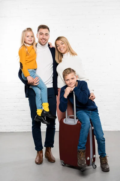 白い背景の上のカメラを見て荷物と冬の休暇に行く準備ができて幸せな家族 — ストック写真