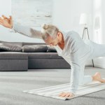 Man die in evenwicht brengen van de kat vormen op yoga mat thuis