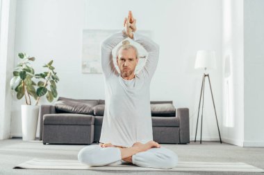 lotus pozisyonu mudra işareti ile oturan ve kameraya bakarak adam 