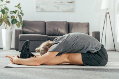 egzersiz ve evde yoga mat germe sportif yetişkin adam yan görünüm