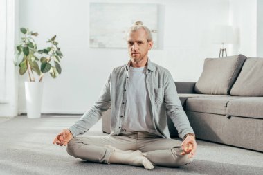 Lotus bulunduğu meditasyon ve evde kameraya bakarak esnek yetişkin adam