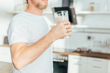 kırpılmış cam protein shake ile evde tutan adam kadeh