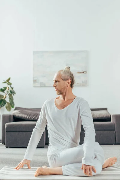 Adult Sportiga Mannen Sitter Ansikte Pose Yogamattan Och Tittar Bort — Stockfoto