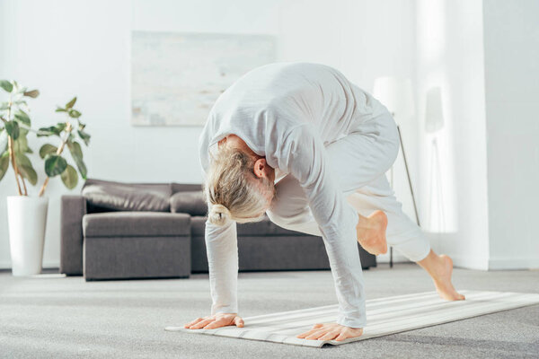 barefoot adult man doing lunge yoga exercise on mat at home