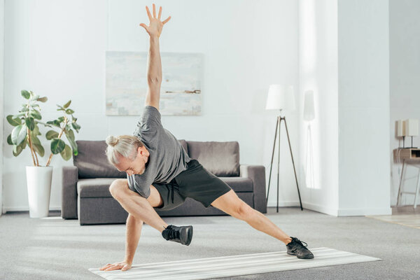 flexible sporty man exercising on yoga mat at home