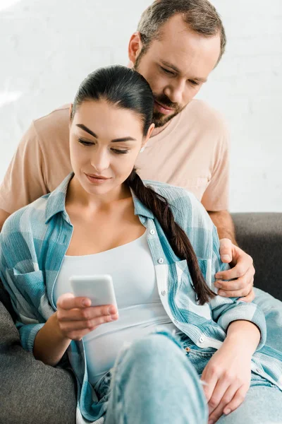 Beautiful Couple Sitting Couch Using Smartphone Home — Free Stock Photo