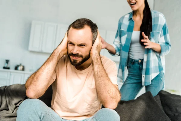 Frustrated Husband Foreground Covering Ears Hands Having Argument Wife Home — Stock Photo, Image