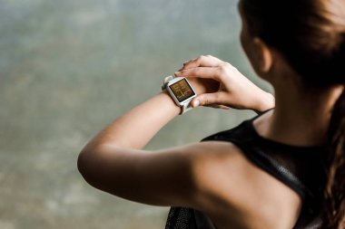cropped view of sportswoman looking at sport smartwatch showing heartbeat rate at gym clipart