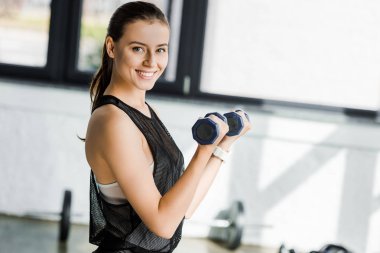 kameraya bakarak ve Spor Merkezi'nde dumbbells ile eğitim güzel gülümseyen sporcumuz