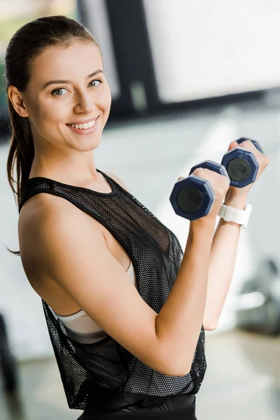 Atrakcyjne Sportsmenka Uśmiechający Się Patrząc Kamery Trening Hantlami Centrum Sportowym — Zdjęcie stockowe