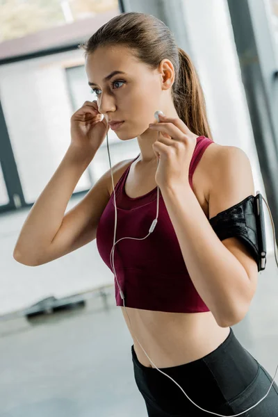 Konzentrierte Sportlerin Smartphone Armbinde Setzt Fitnessstudio Kopfhörer Auf — Stockfoto