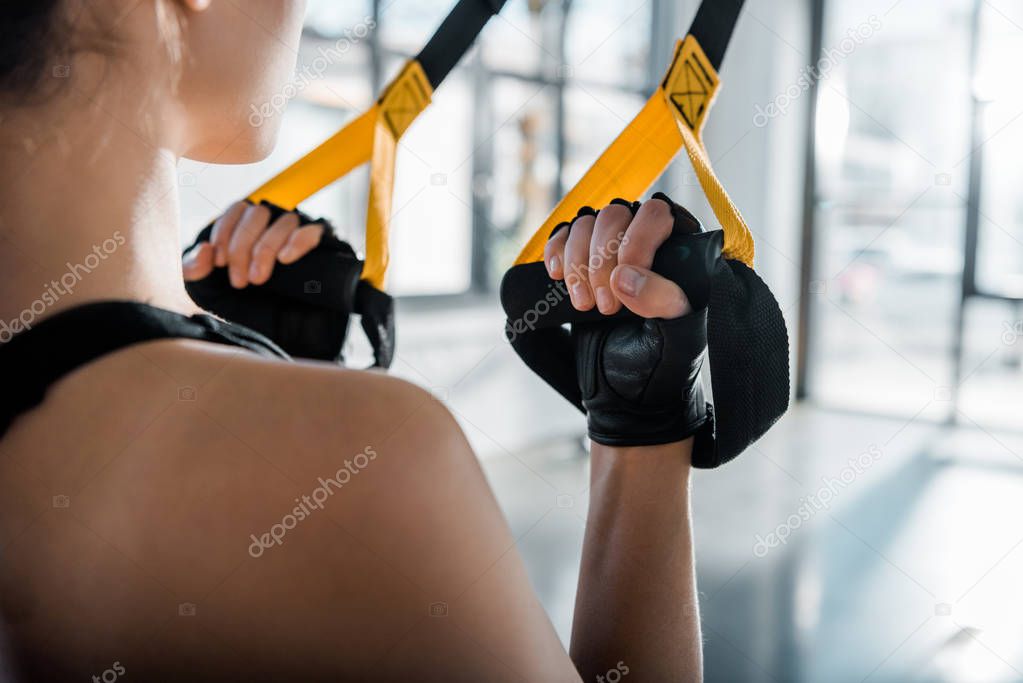 cropped view of sportswoman training with resistance bands at gym