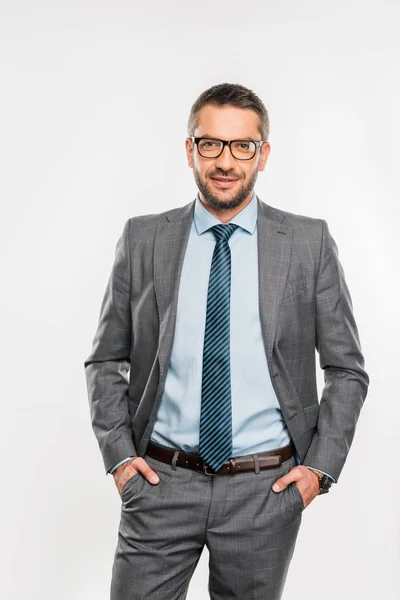 Handsome Businessman Suit Eyeglasses Standing Hands Pockets Smiling Camera Isolated — Stock Photo, Image