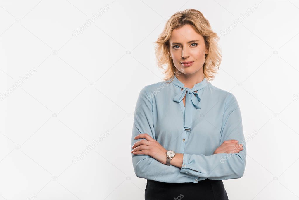 beautiful businesswoman standing with crossed arms and smiling at camera isolated on white