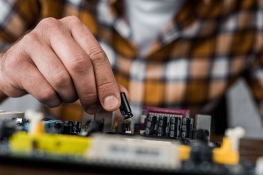 cropped shot of computer engineer taking transistor from motherboard clipart